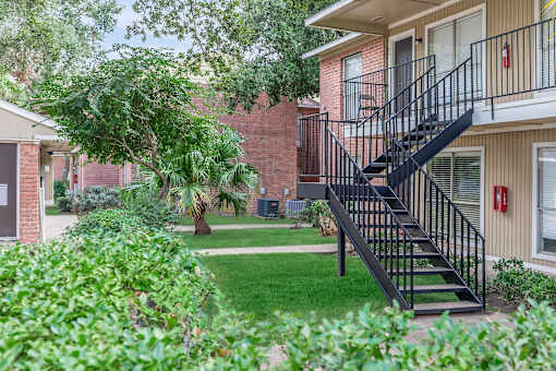 A black metal staircase leads up to a door on a brick building.