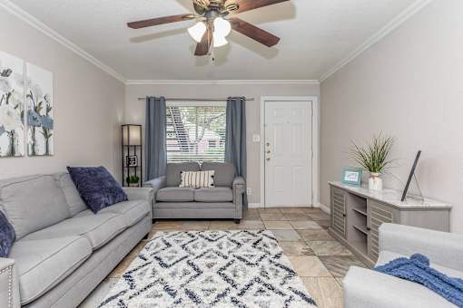 A living room with a grey couch and a ceiling fan.