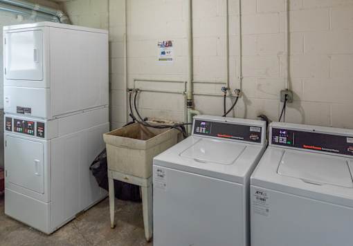 A white washing machine sits next to a white dryer in a laundry room.