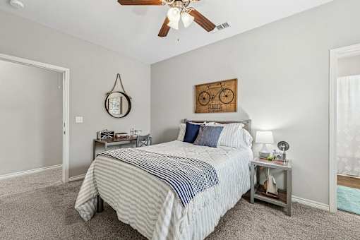 A bedroom with a bed, nightstand, and a ceiling fan.