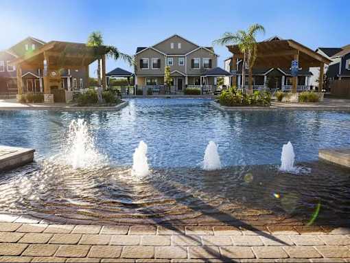 A fountain in the middle of a pool surrounded by houses.