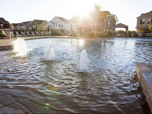 A fountain in the middle of a pool surrounded by houses.