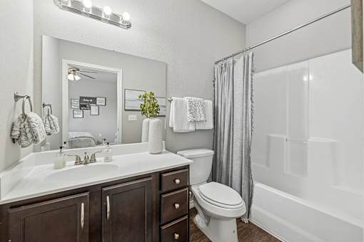 A white bathroom with a toilet, sink, and mirror.