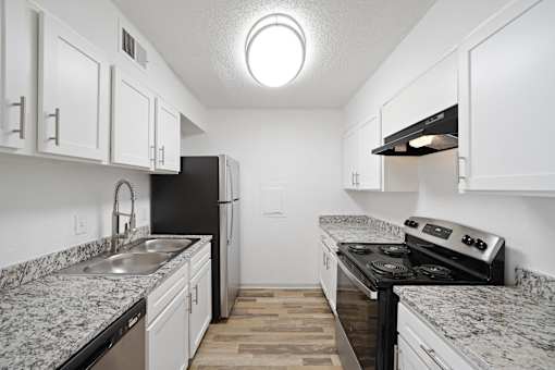 A kitchen with black appliances and white cabinets.