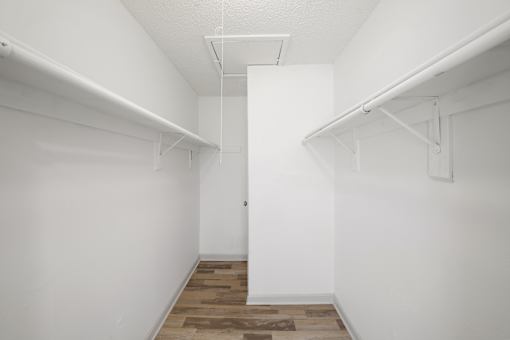 A white hallway with a door in the middle and a wooden floor.