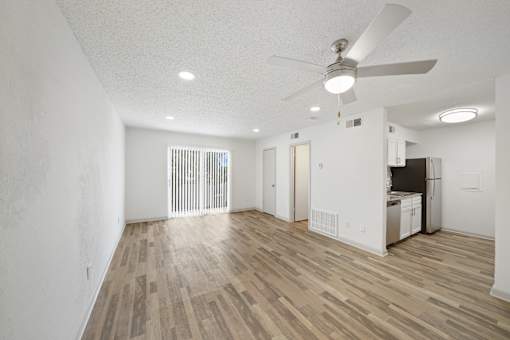 A room with a ceiling fan and wooden flooring.
