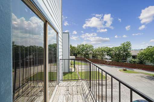 A balcony with a view of a street and trees.