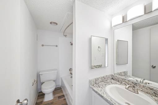 A white bathroom with a toilet, sink, and mirror.