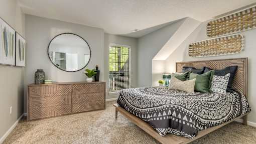A bedroom with a bed, dresser, and mirror.