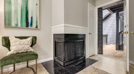 A green chair with a white pillow is in front of a fireplace in a room.