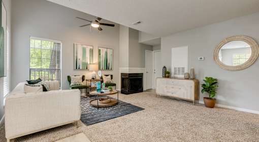 A living room with a beige sofa, a fireplace, and a mirror on the wall.