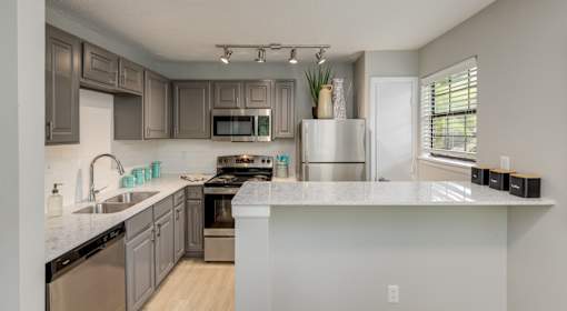 A modern kitchen with a white countertop and stainless steel appliances.