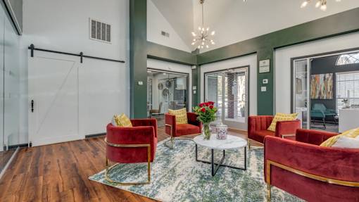 A living room with red chairs and a glass table.
