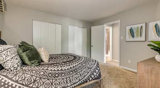 A bedroom with a bed, a dresser, and a painting on the wall.