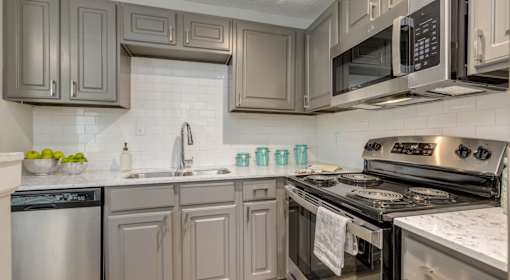 A kitchen with a stove, dishwasher, and microwave.