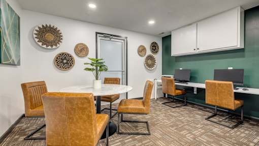A room with a white table surrounded by chairs and a green wall.
