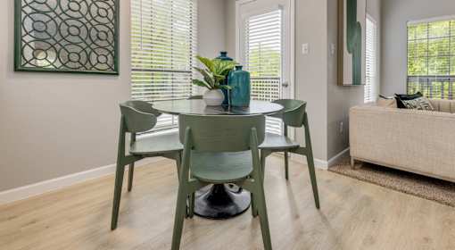 A dining room with a green table and chairs.