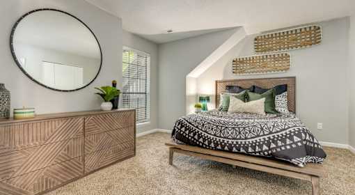 A bedroom with a bed, dresser, and mirror.
