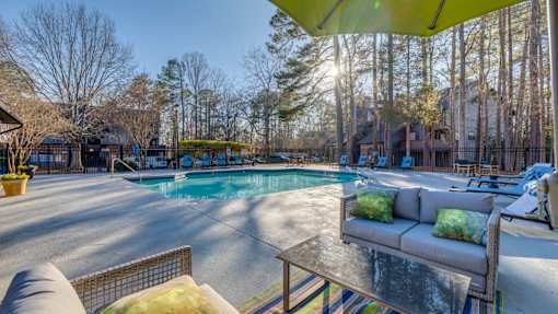 A sunny day at the poolside with a yellow umbrella providing shade.