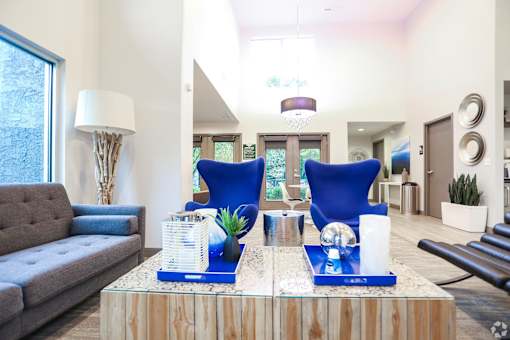 A living room with a grey couch, a wooden coffee table, and blue chairs.