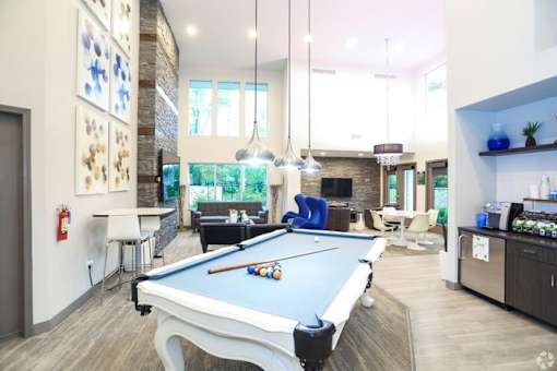 A pool table is in the middle of a room with a bar and a fire extinguisher on the wall.