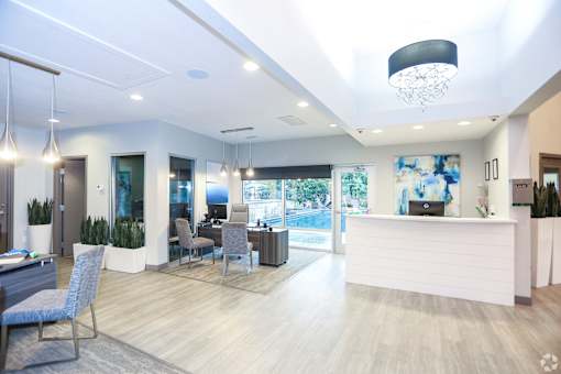 A reception area with a white reception desk and blue chairs.