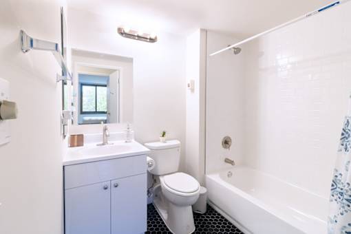 A white toilet sits next to a white bathtub in a bathroom.