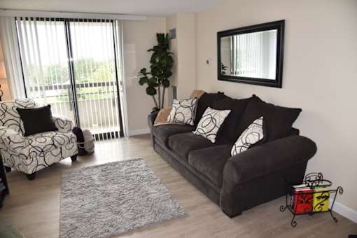 A living room with a grey couch and a grey and white patterned chair.