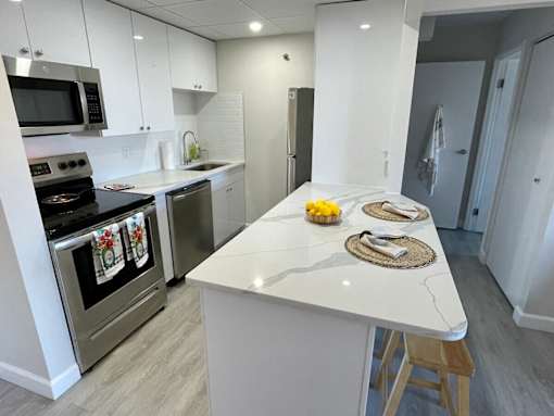 A kitchen with a white countertop and stainless steel appliances.