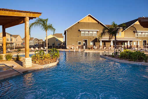 A pool in front of a building with a clear blue sky.