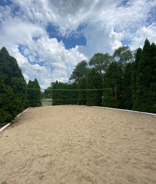a volleyball court in a park with trees and a cloudy sky at Village Club on Franklin, Southfield Michigan