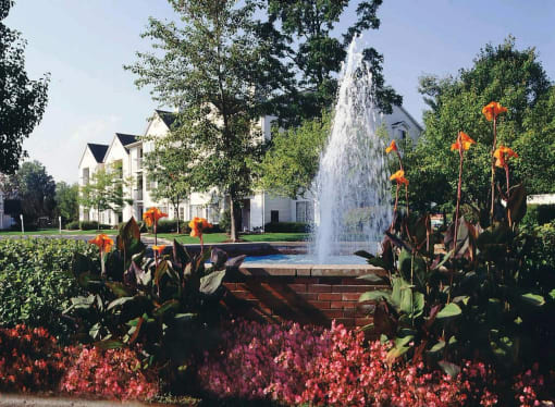 a fountain in the middle of a park with flowers at Village Club on Franklin, Southfield, 48034
