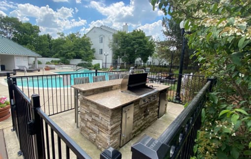a patio with a grill and a swimming pool at Village Club on Franklin, Southfield