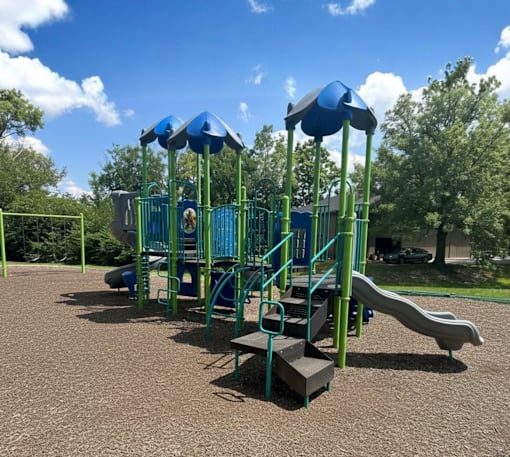 A playground with a green and blue slide and a blue canopy.