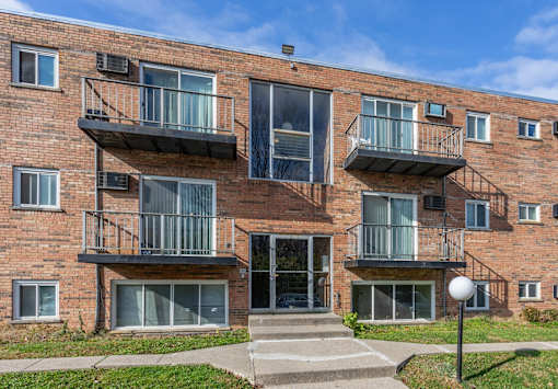 A red brick building with balconies and a clear sky in the background.