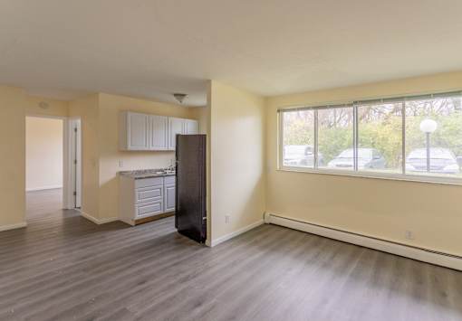 A spacious living room with a kitchenette and a view of the street outside.
