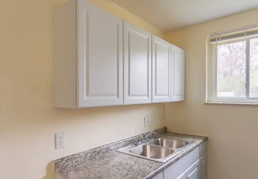 A kitchen with a granite countertop and white cabinets.