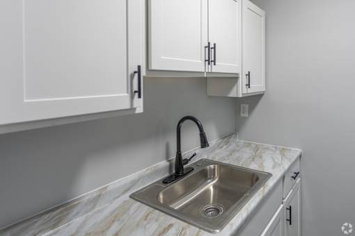 A kitchen with a marble countertop and a stainless steel sink.