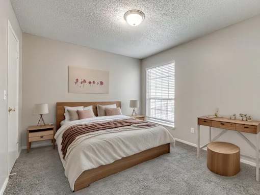 A bedroom with a bed, desk, and window.