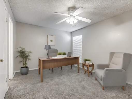 A room with a ceiling fan, a desk, a chair, and a potted plant.