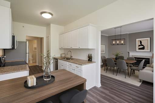 A modern kitchen with a wooden table and grey chairs.