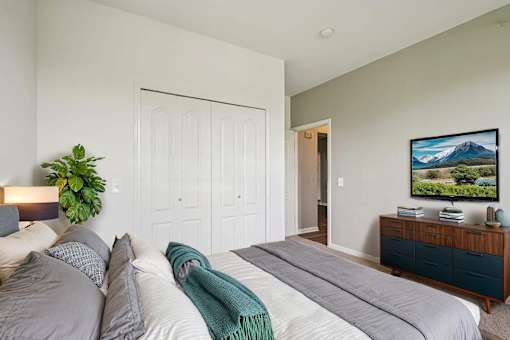 A bedroom with a large bed and a flat screen TV mounted on the wall.
