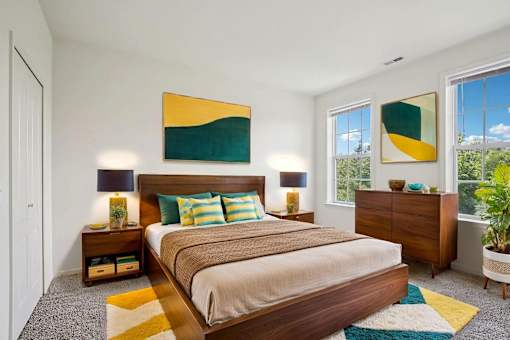 A bedroom with a bed, nightstands, and a large painting on the wall.
