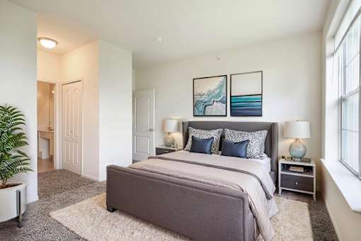 A bedroom with a large bed and a potted plant.