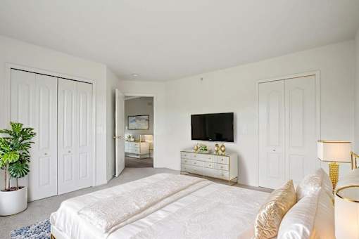 A white bedroom with a large bed and a television.