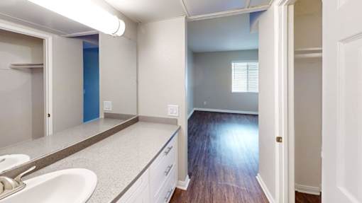 A bathroom with a sink, mirror, and wooden floors.