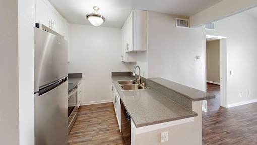A kitchen with a stainless steel refrigerator and a countertop with a sink.