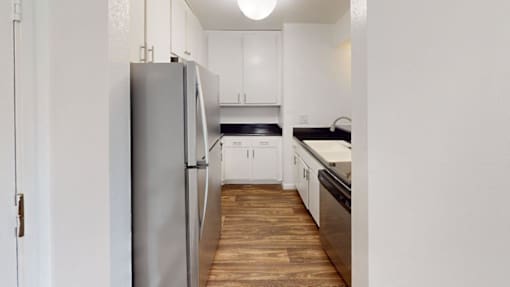 A kitchen with a refrigerator and wooden floors.