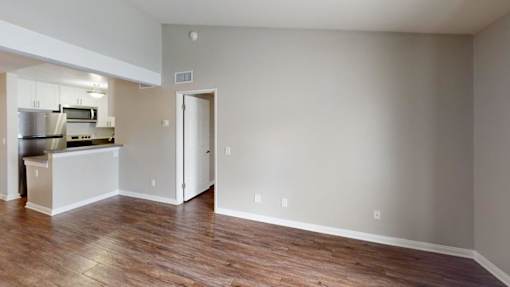 A kitchen with a refrigerator, microwave, oven, and cabinets is visible through an open door.