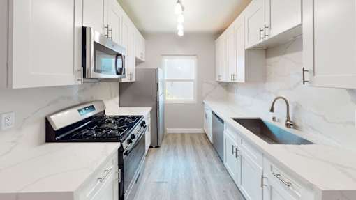 A kitchen with white cabinets and marble countertops.